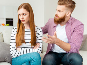 Young couple in a disagreement, with the man gesturing and the woman looking away.