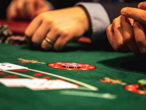 Hands of poker players at a casino table, with chips and cards in view.