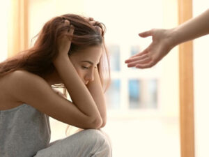 Distraught woman with a hand reaching out to her, offering help or comfort.