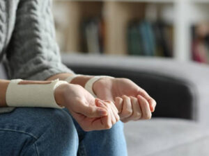 Person sitting with bandaged wrists, suggesting recovery or distress.